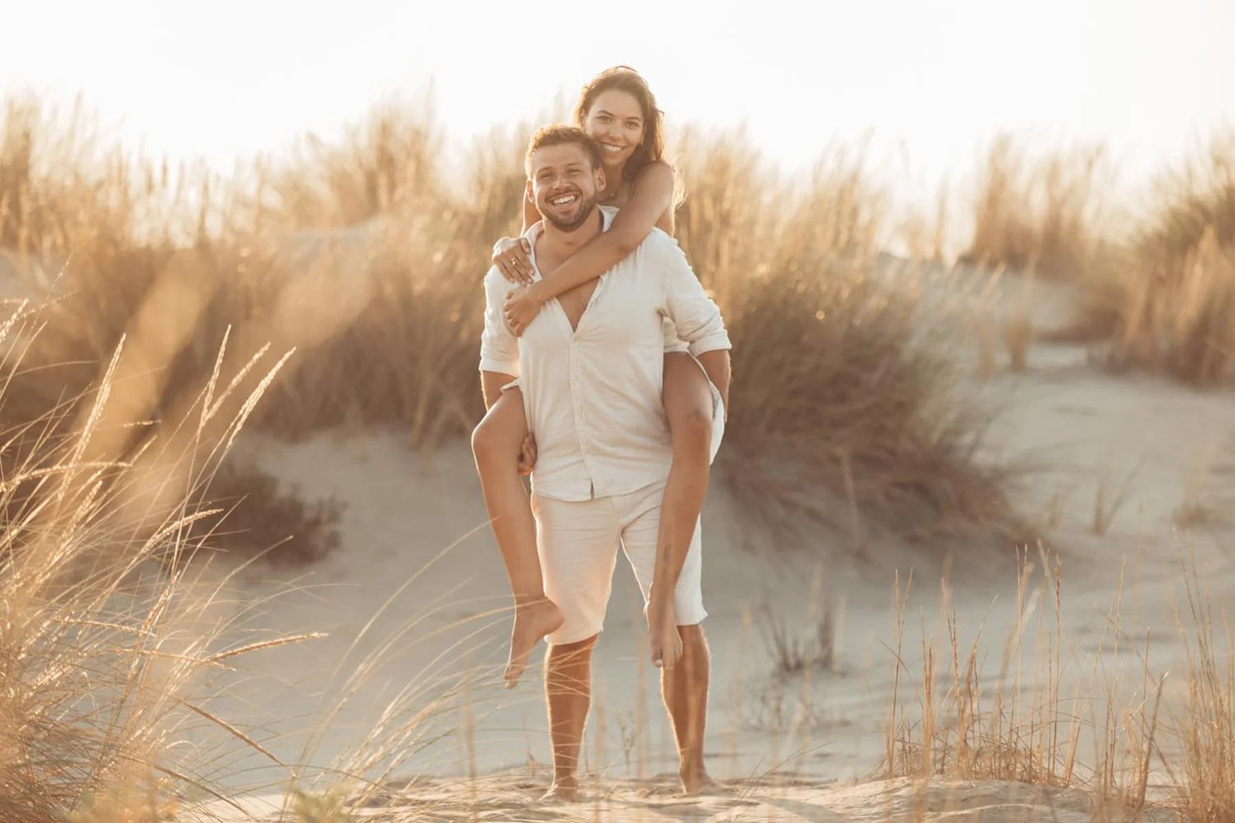 Photo couple spontanée - piggyback et éclats de rire sur la plage
