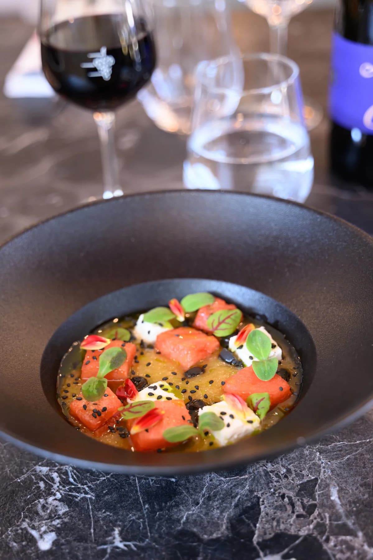 Photo culinaire bol noir entrée gastronomique avec verre de vin rouge