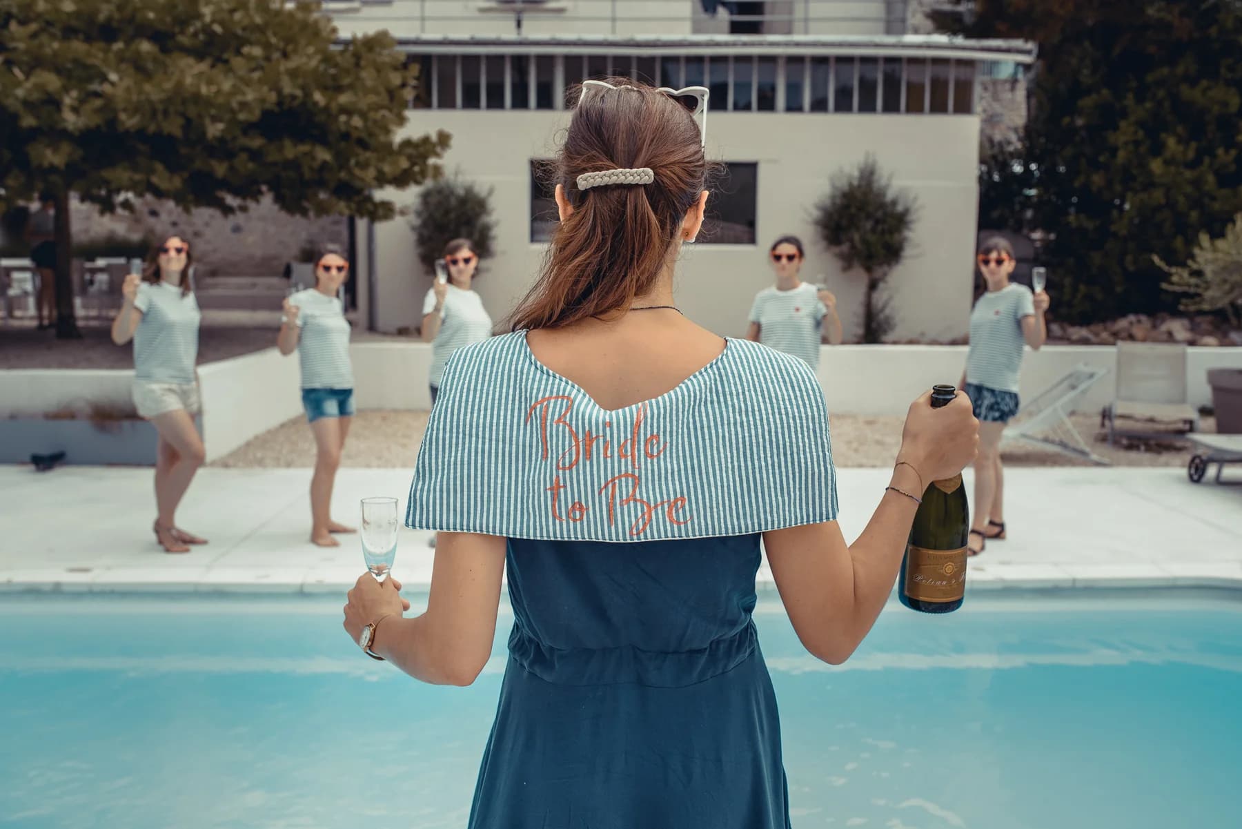 EVJF bride to be de dos avec champagne et copines au bord de la piscine