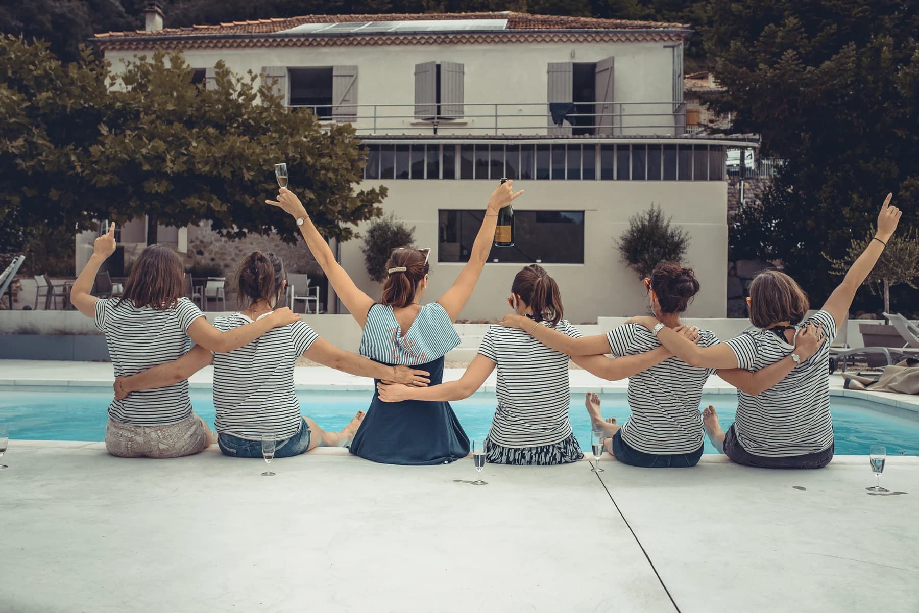 Séance photo EVJF copines de dos au bord de la piscine bras levés