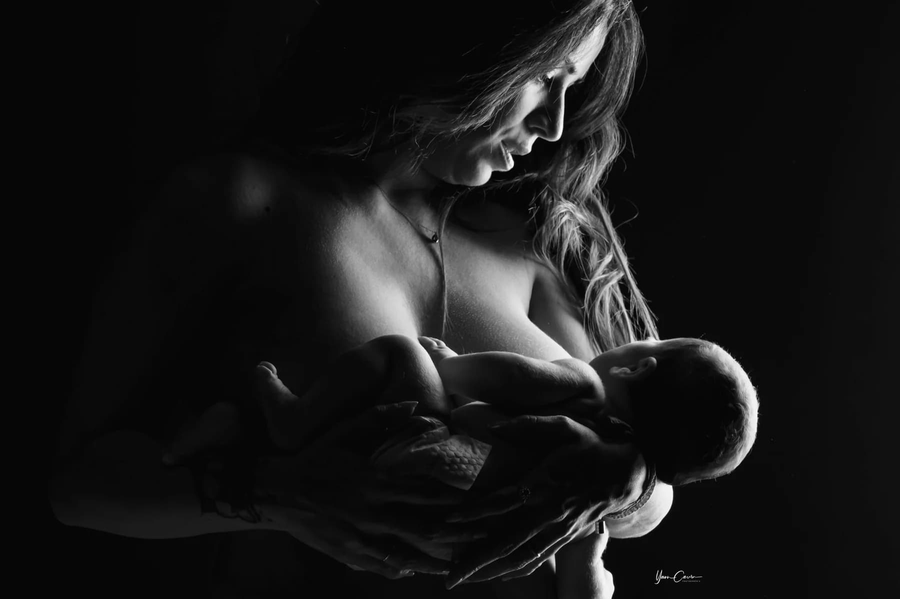 Maman berçant son nouveau-né en clair-obscur