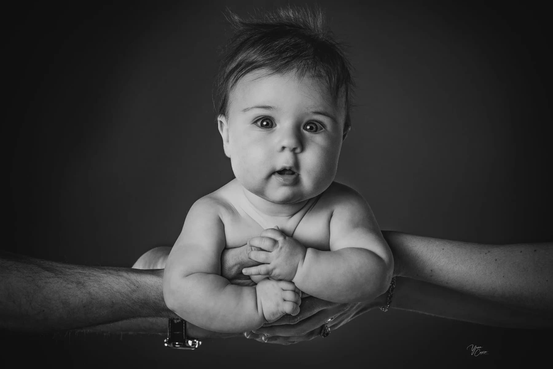 Portrait noir et blanc d'un bébé dans les mains de ses parents