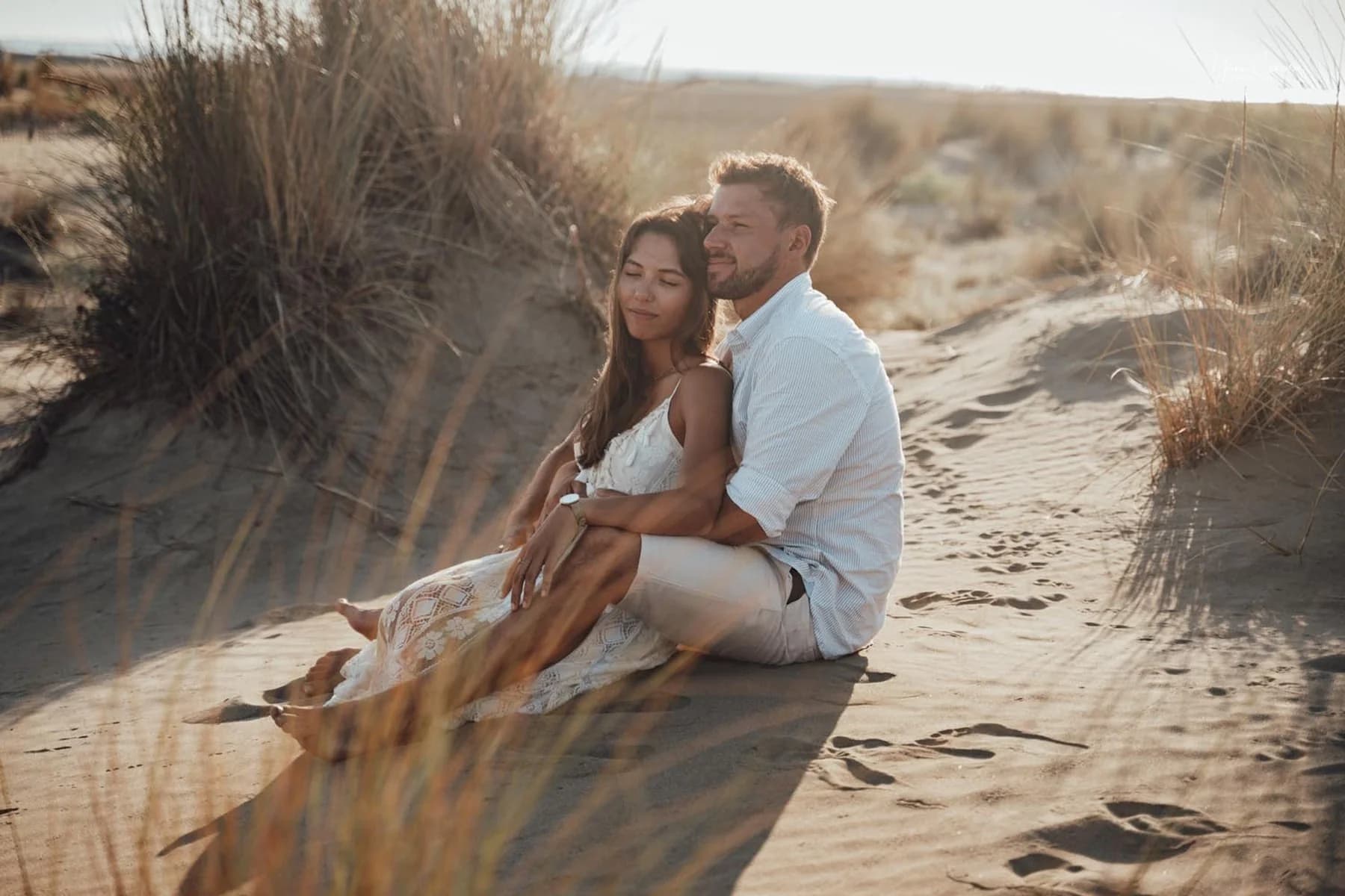 Couple assis dans les dunes de la plage de l'Espiguette, moment de tendresse en contre-jour