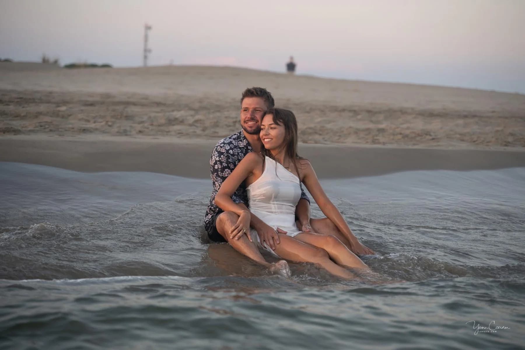 Couple assis dans l'eau, regard caméra et sourires chaleureux, séance photo en Camargue