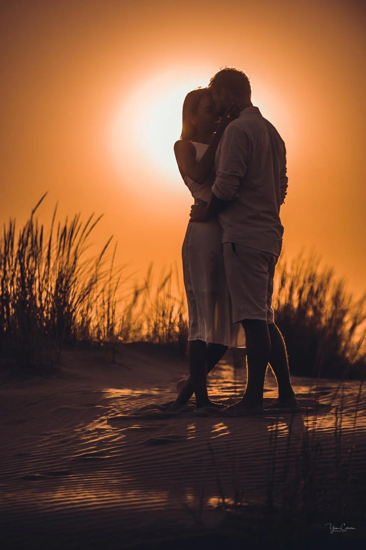 Silhouette d'un couple devant le soleil couchant orange sur la plage du Grau-du-Roi