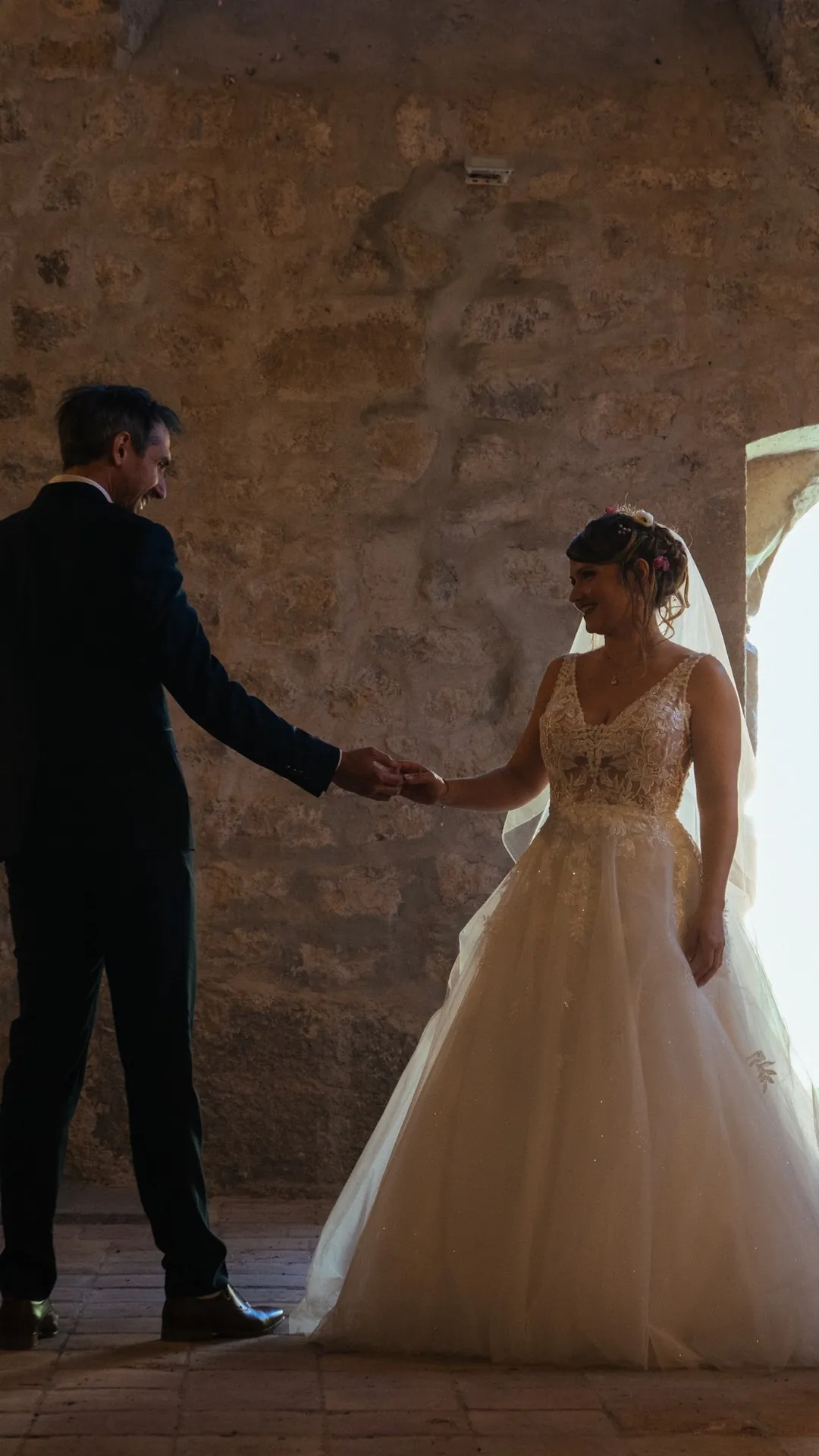 Photographe de mariage en Ardèche : les mariés se tiennent la main dans la salle en pierre du château de Saint-Alban-Auriolles, près de Ruoms