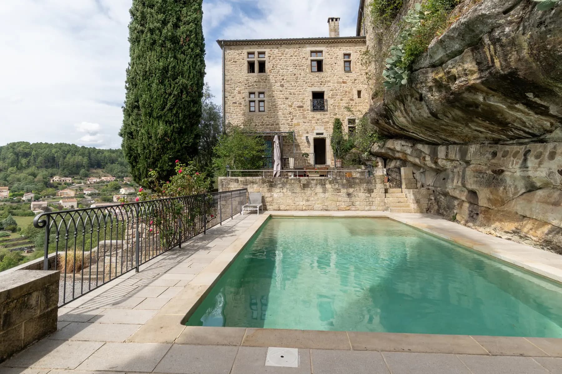 Piscine et façade d'un château adossé à la falaise à Ucel — photographe immobilier de prestige en Ardèche