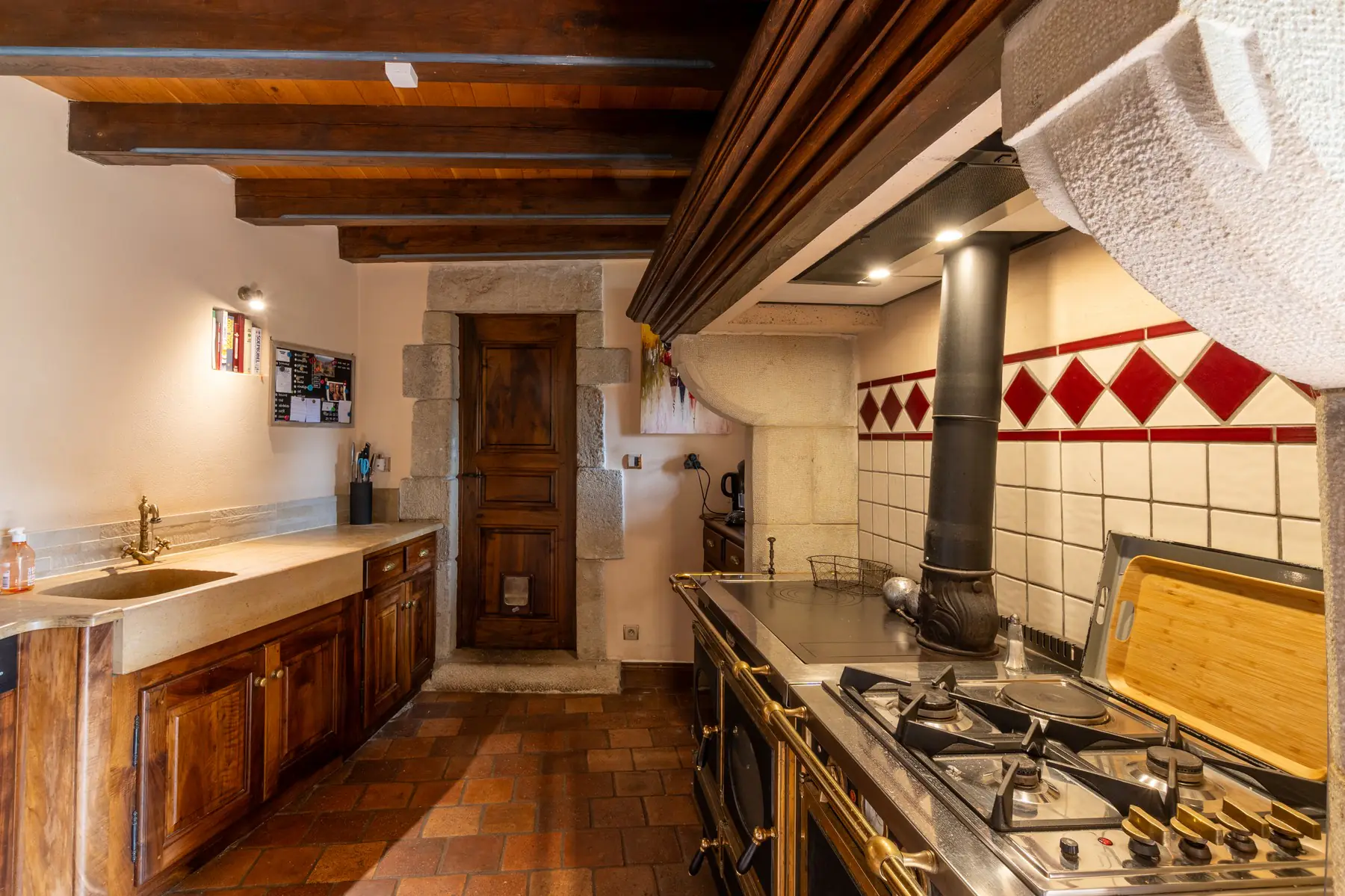 Cuisine de caractère avec piano de cuisson et évier en pierre — château à Ucel, Ardèche