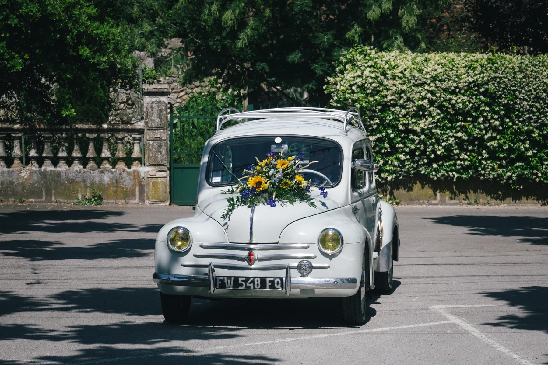 Mariage à Saint-Alban-Auriolles : Renault 4CV blanche décorée de tournesols devant la mairie.