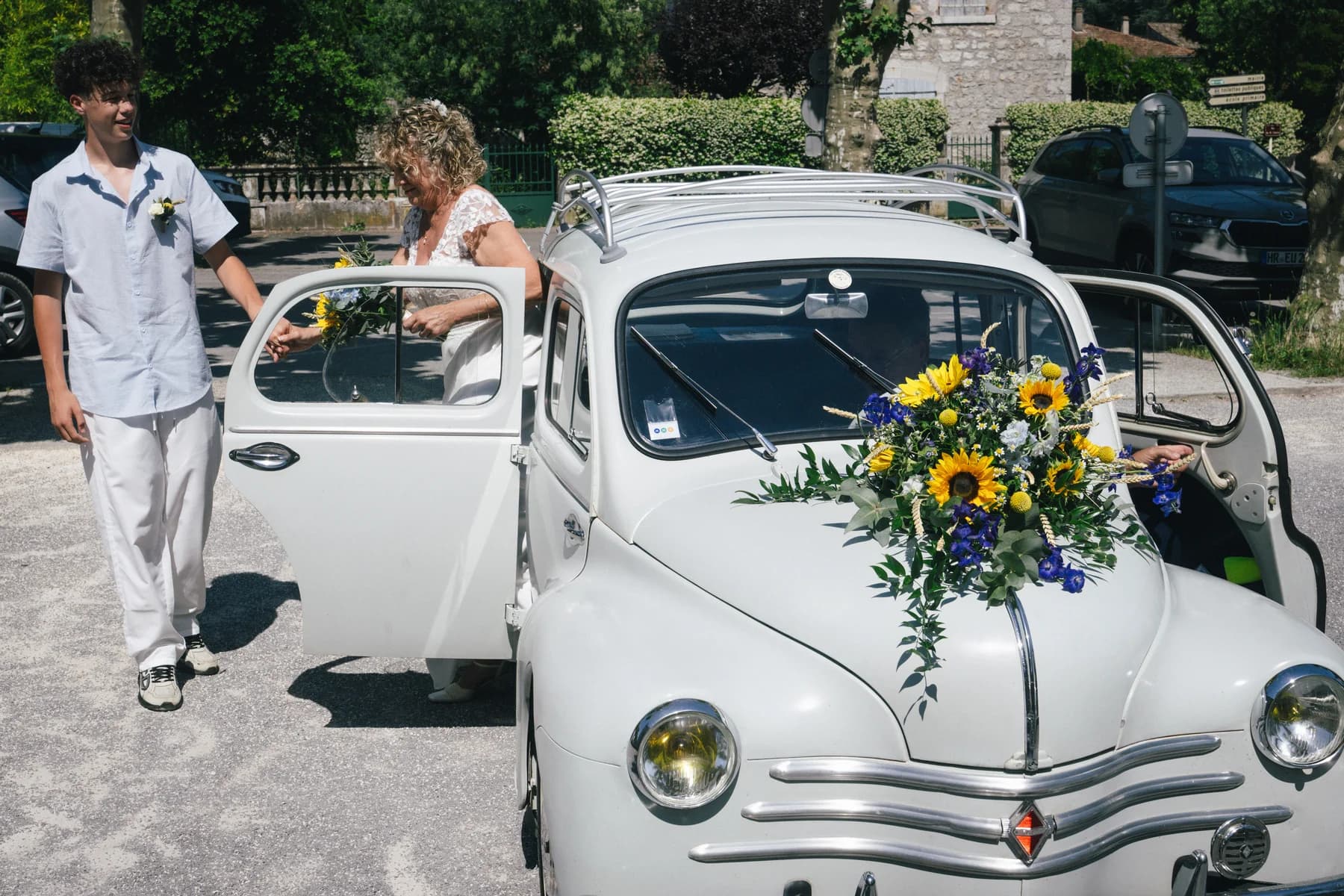 Mariage Sud Ardèche : la mariée descend de la 4CV blanche ornée de tournesols.