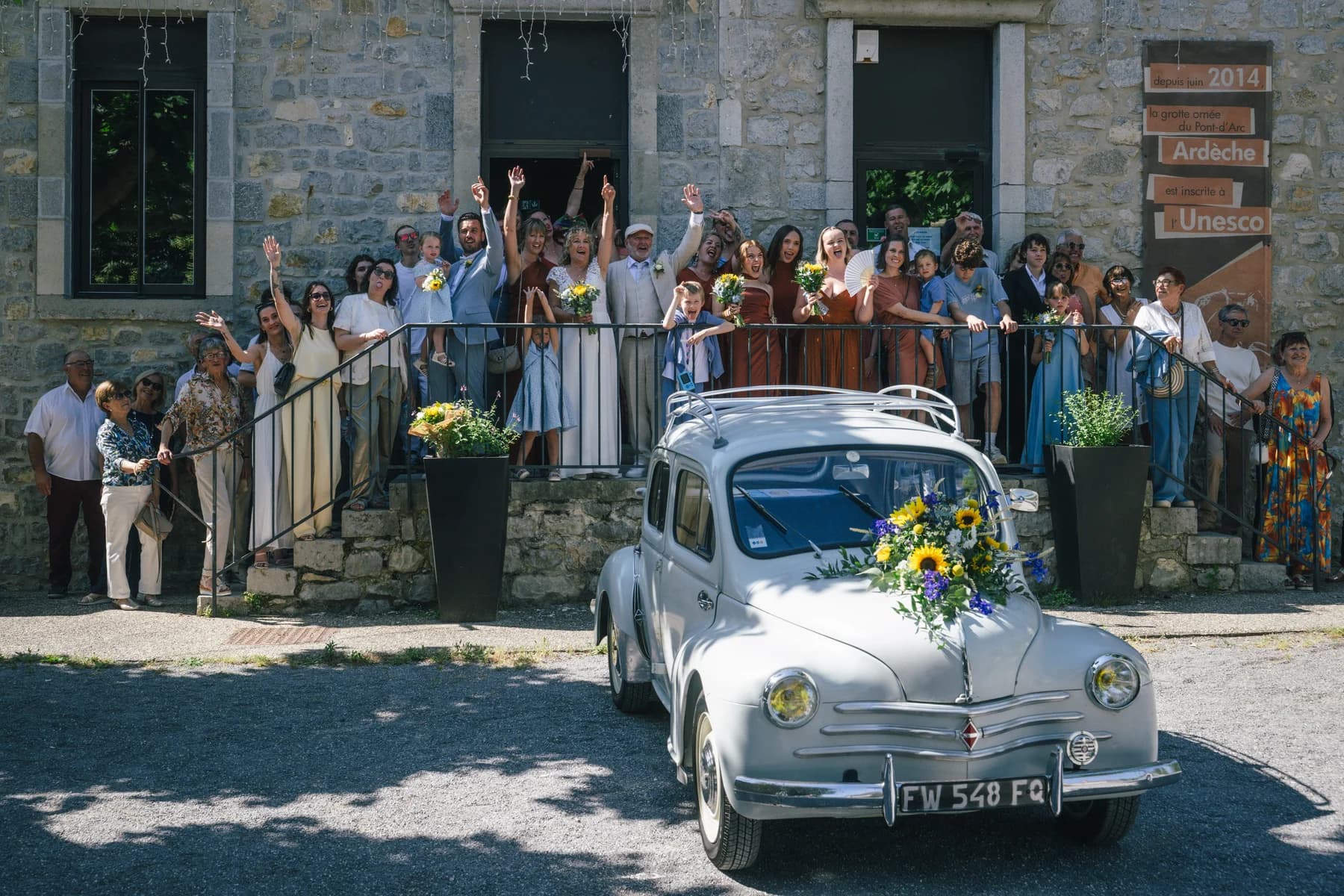 Mariage Sud Ardèche : la 4CV blanche entourée des invités à la sortie de la mairie.