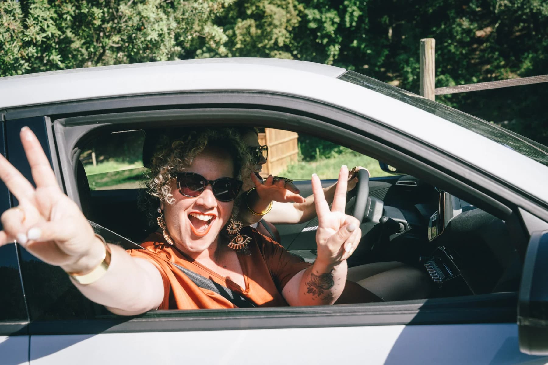 Mariage Sud Ardèche : invitée joyeuse à la fenêtre d'une voiture pendant le cortège.