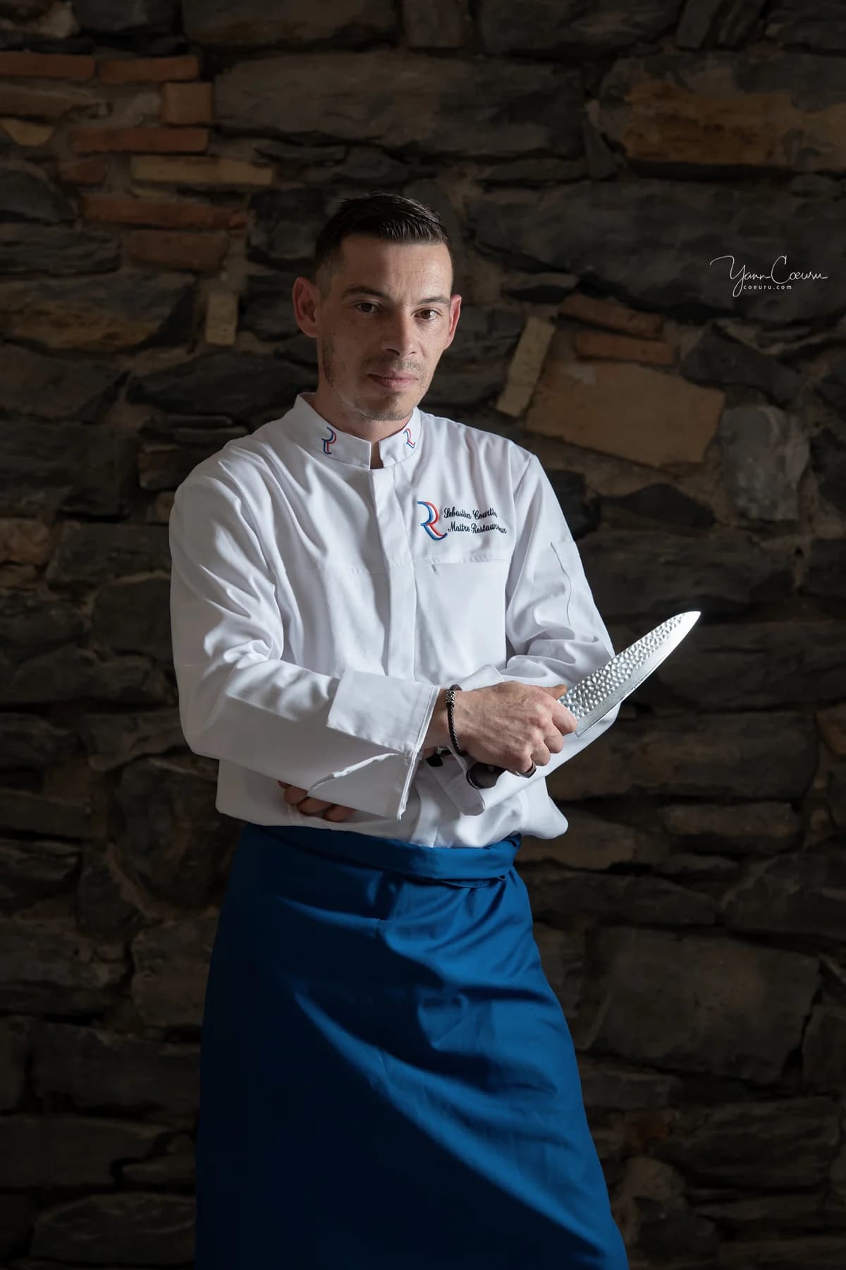 Chef restaurateur tenant un couteau, reportage de métier sur son lieu de travail en Ardèche.