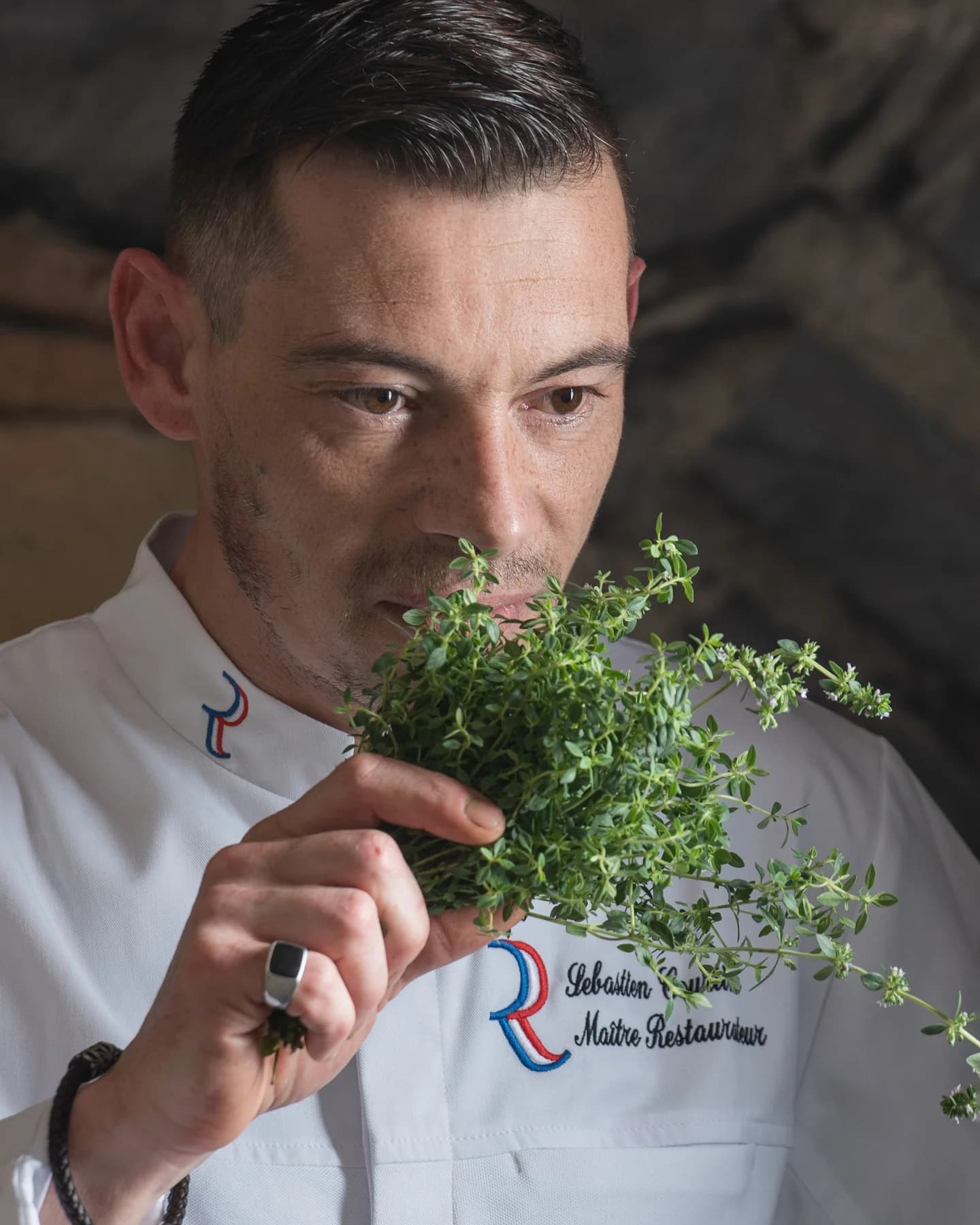 Chef restaurateur humant un bouquet d'herbes fraîches, reportage d'entreprise en Ardèche.