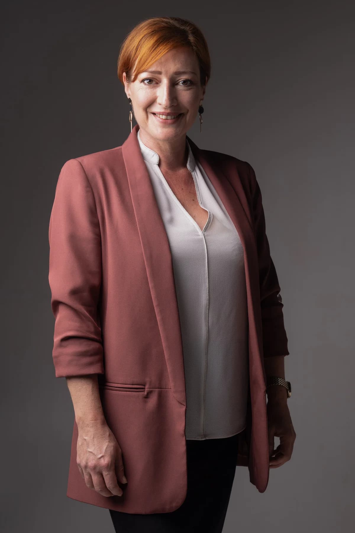 Portrait professionnel d'une femme en blazer rose, studio fond neutre en Ardèche.