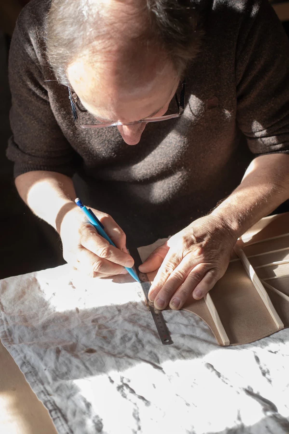 Artisan Entreprise à Saint Genest de Bauzon traçant une mesure au crayon sur une pièce de bois en atelier.
