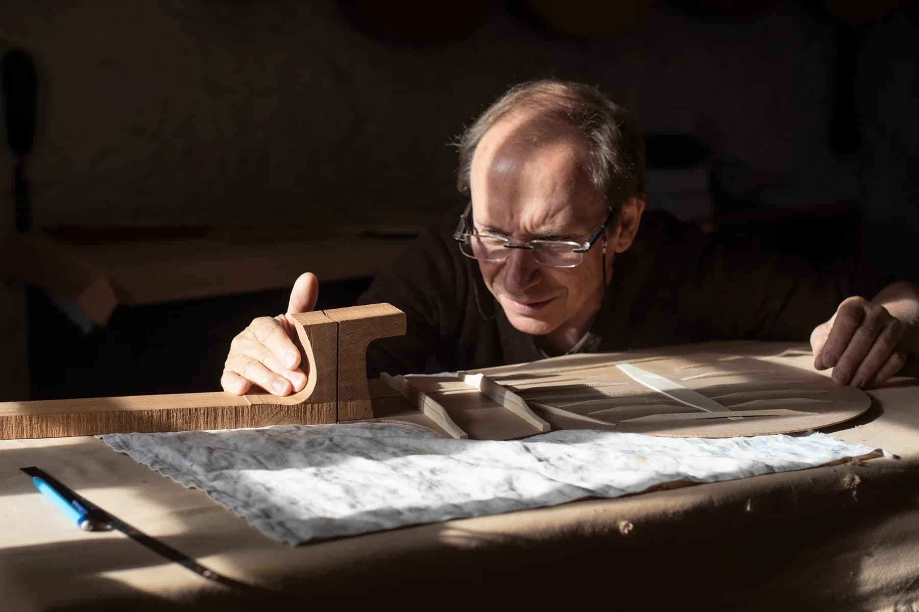 Artisan luthier concentré dans son atelier à Saint genest de bauzon, reportage Entreprise en lumière naturelle.