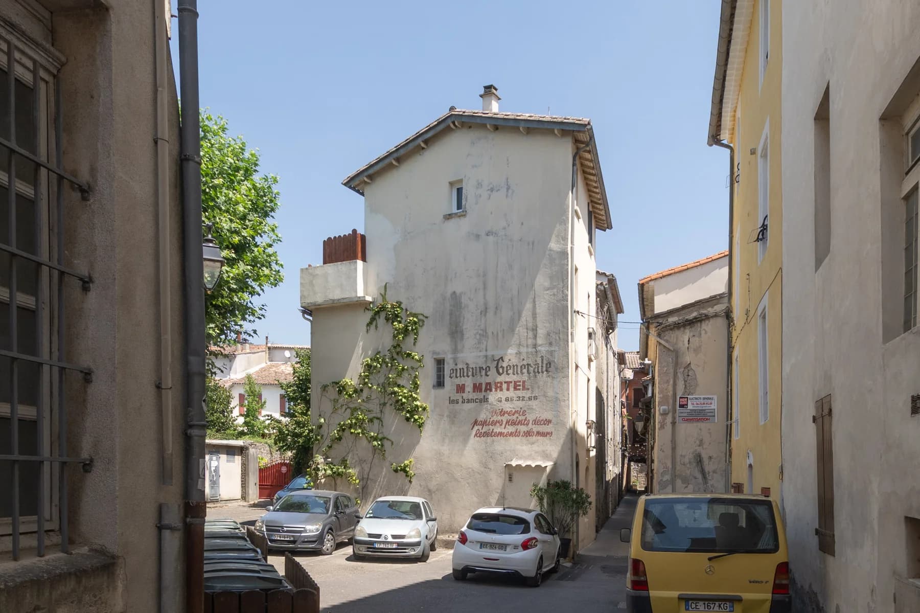 Immobilier Vaucluse : façade ancienne avec publicité peinte dans une ruelle provençale ensoleillée.