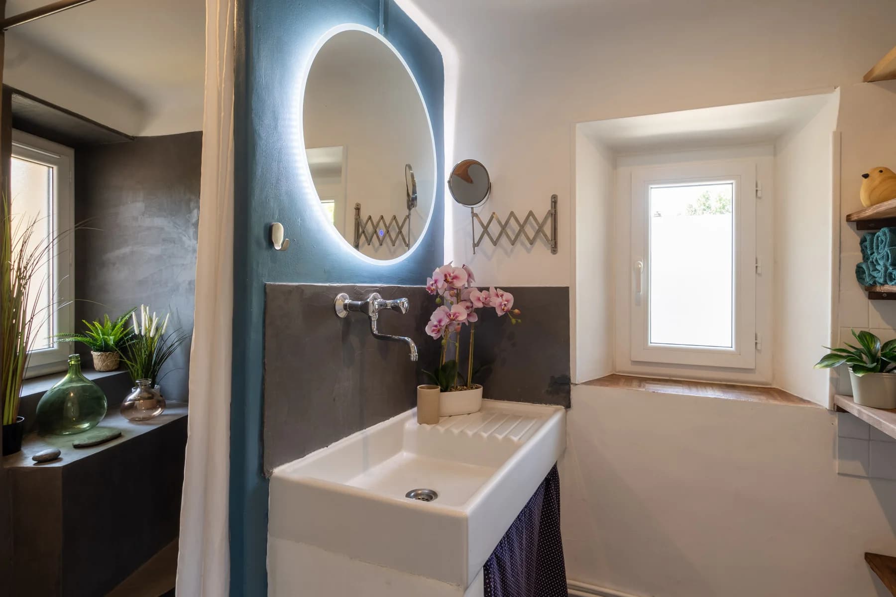 Immobilier Vaucluse : salle de bain lumineuse avec miroir LED rétroéclairé et orchidée rose, par Yann Cœuru Photographie.