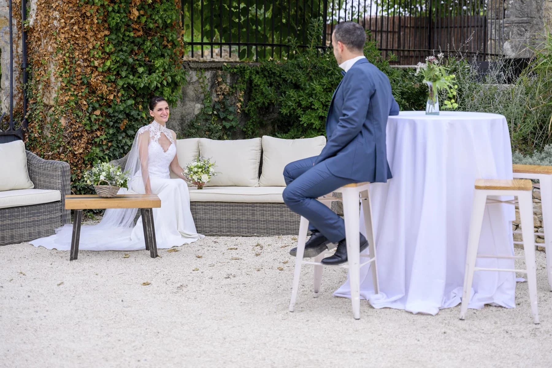 Mariage en Ardèche : couple en tenue élégante dans jardin avec ivy et mobilier design, ambiance intime et naturelle