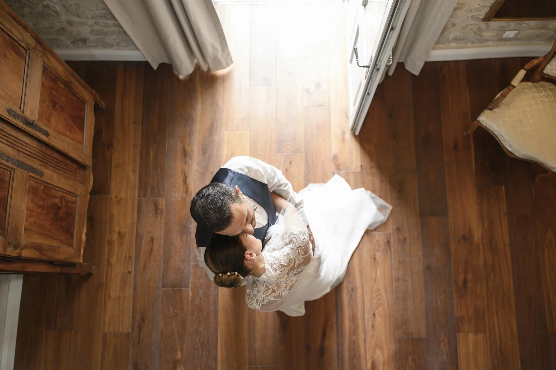 Couple de mariés s'embrassant en intérieur lumineux, mariage en Ardèche avec parquet chaleureux