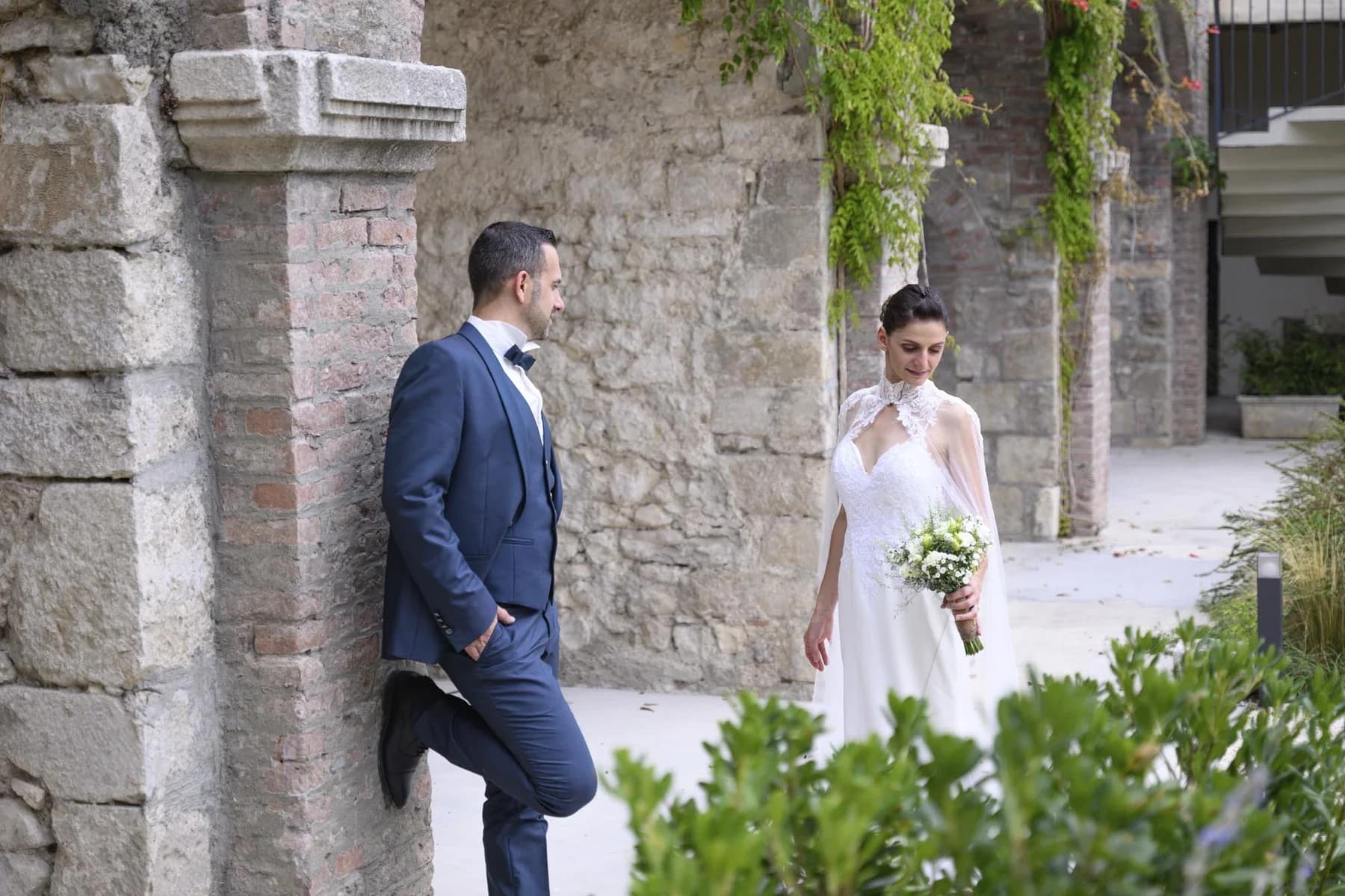 Couple mariage au Domaine de la Bedosse, à Alès devant murs pierre ancienne, mariée robe blanche bouquet, marié costume bleu