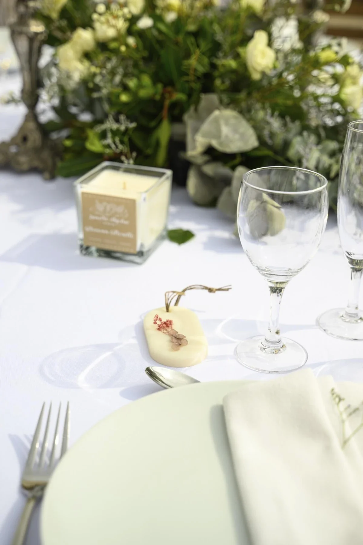Décoration élégante de mariage au Domaine de la Bedosse, à Alès, table blanche avec verres, fleurs blanches et marque-place