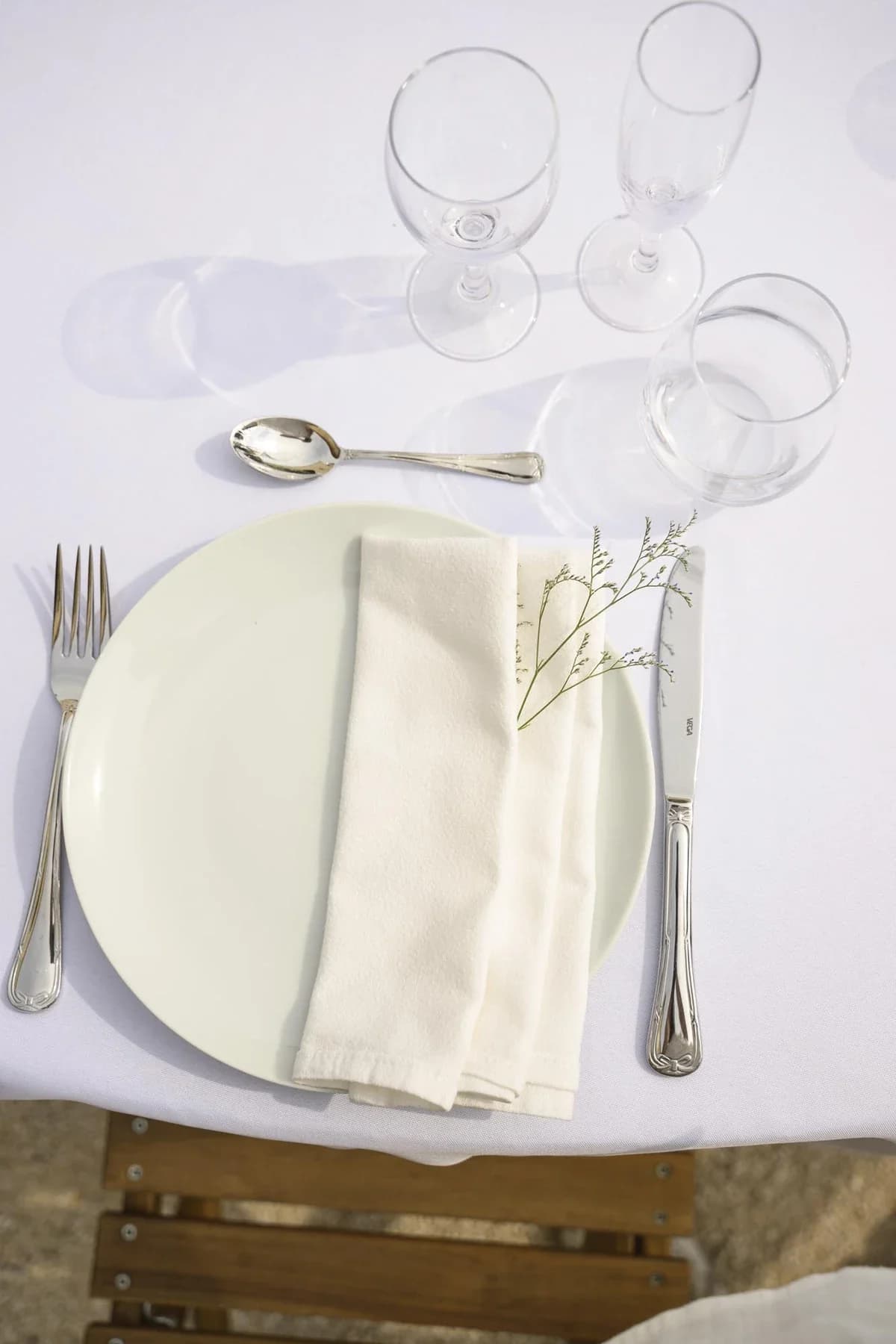 Mise en place élégante mariage au Domaine de la Bedosse, à Alès avec assiette blanche, verres et décoration florale minimaliste