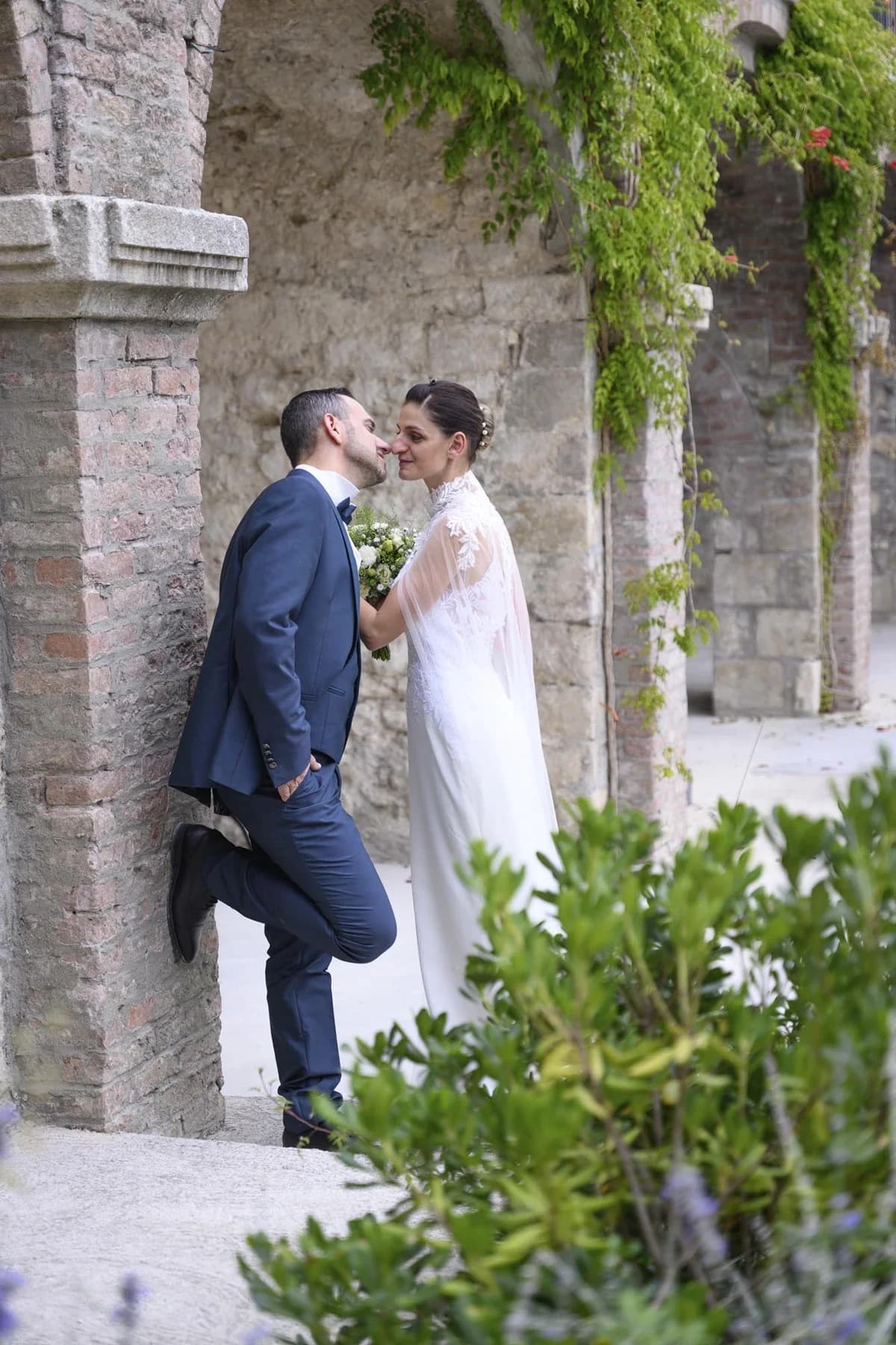 Couple mariage en Ardèche s'embrassant dans ruelles pittoresques avec lierre et pierre ancienne
