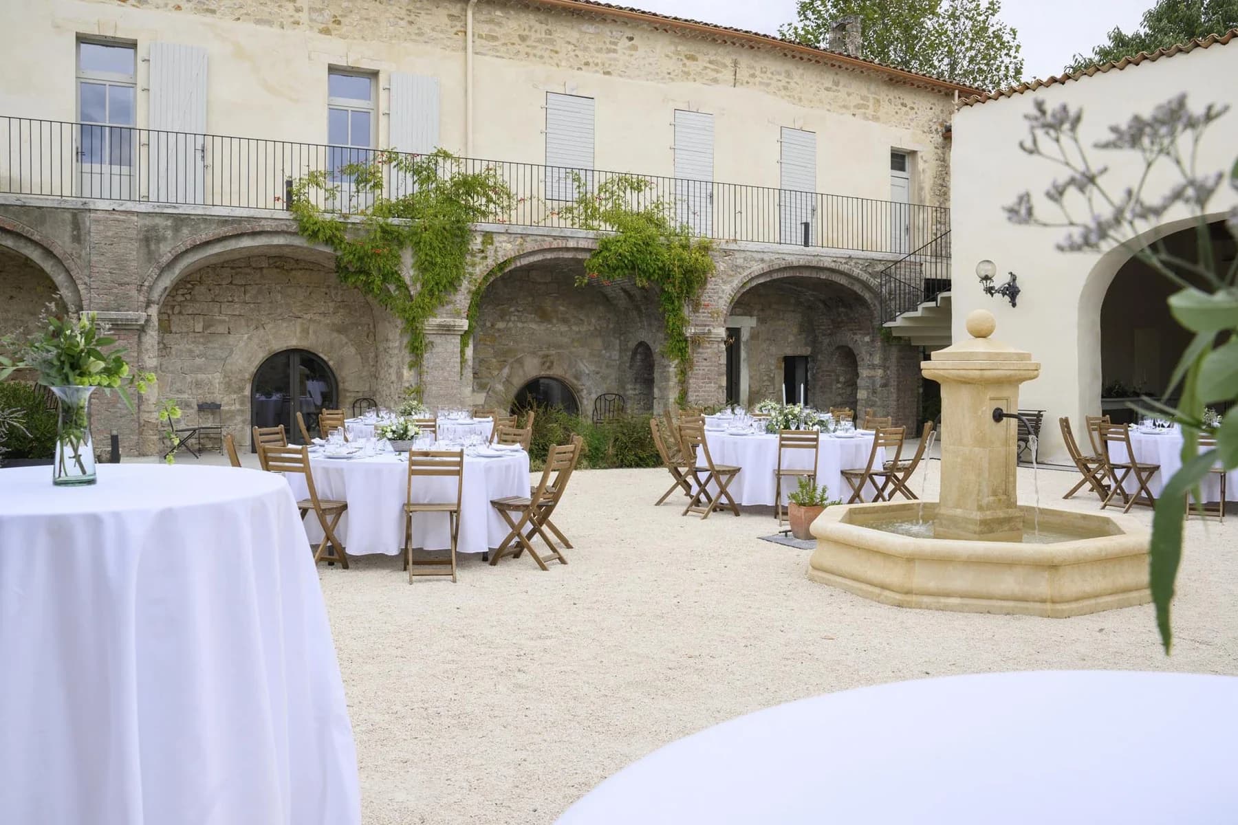 Réception mariage au Domaine de la Bedosse, à Alès dans cour intérieure avec tables blanches et arches en pierre