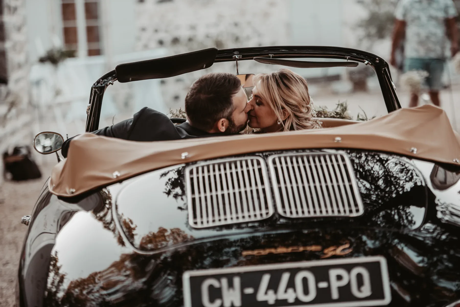 Mariages à Aubenas, couple s'embrassant dans un cabriolet vintage noir, ambiance romantique et élégante.