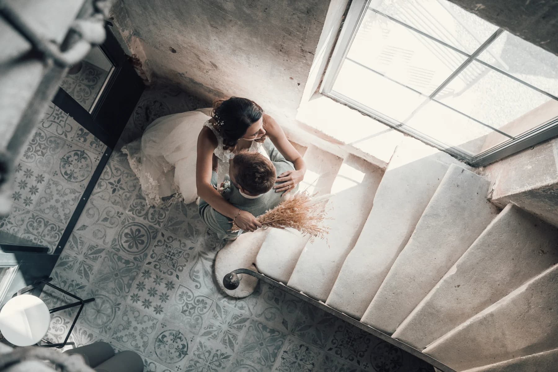 Mariages au domaine du trusquin Pierrelatte Drôme, couple enlacé au pied d'un escalier en pierre vu du dessus.