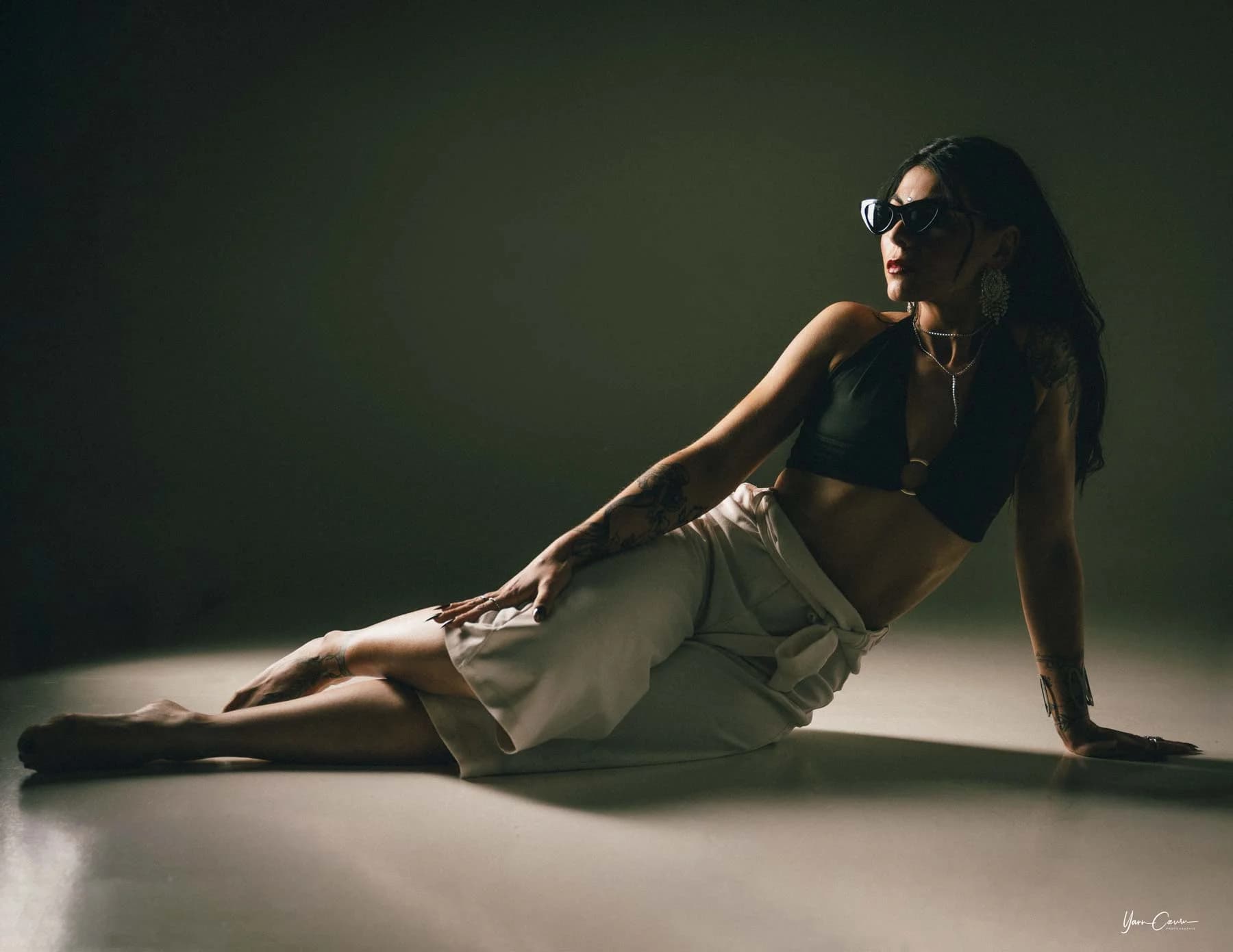 Femme en studio posant allongée, photothérapie moderne avec lumière naturelle et fond vert