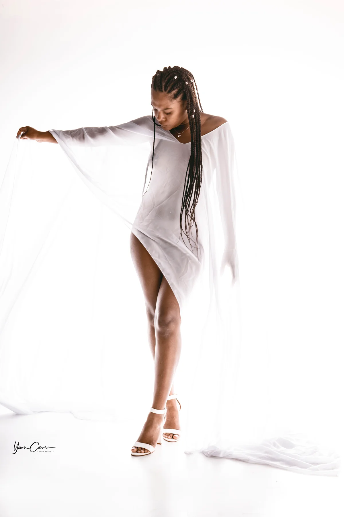 Femme en robe blanche fluide dans studio, photothérapie expressive en lumière douce et minimaliste