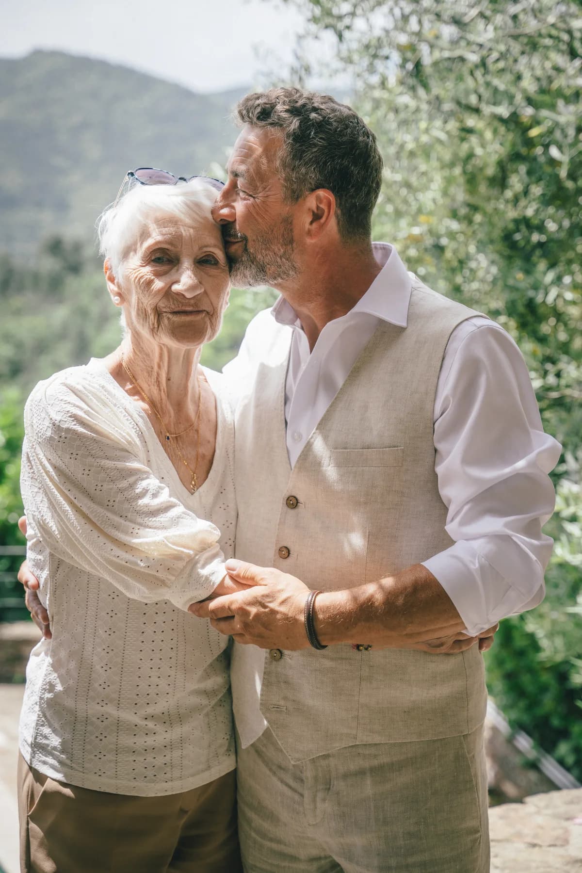 Angelo embrasse la grand-mère sur la tempe, un moment de tendresse — séance de fiançailles à Saint-Mélany (Ardèche)
