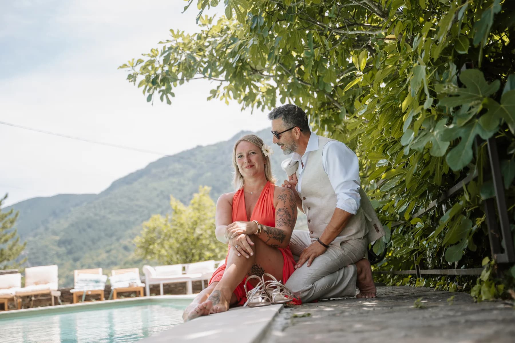 Cathia et Angelo assis au bord du bassin face à la vallée — séance de fiançailles à Saint-Mélany (Ardèche)