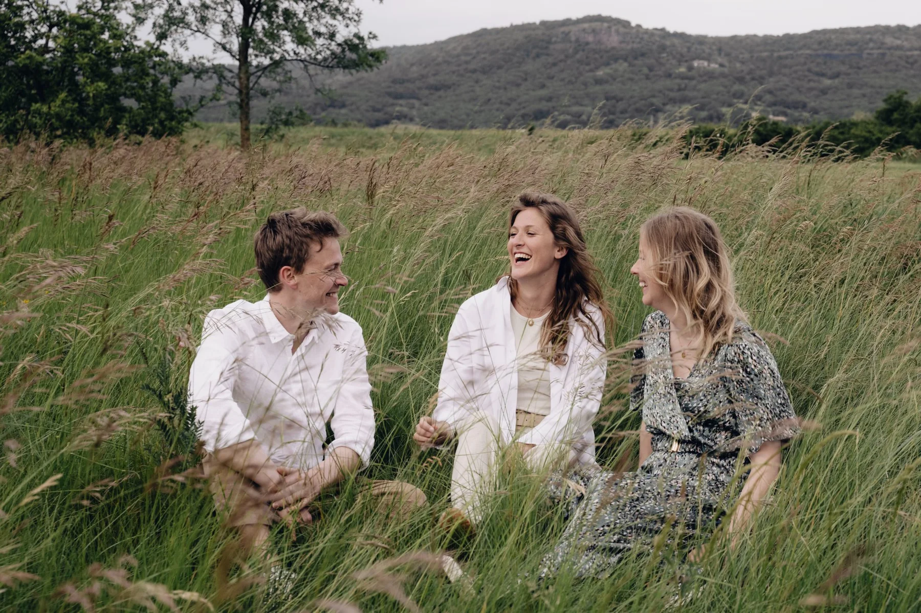 Photo famille trio riant dans les herbes avec montagnes ardéchoises