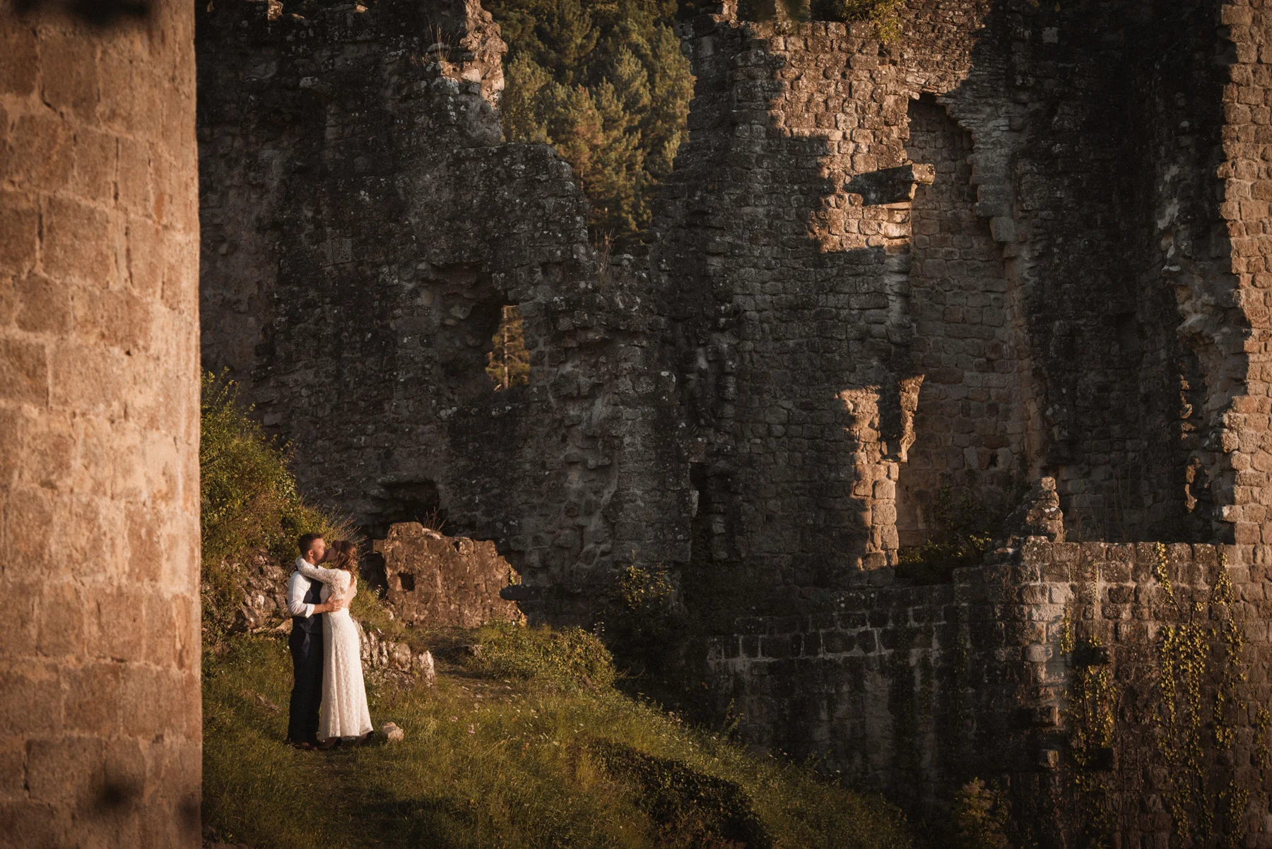 Couple de mariés devant des ruines au coucher du soleil en Ardèche